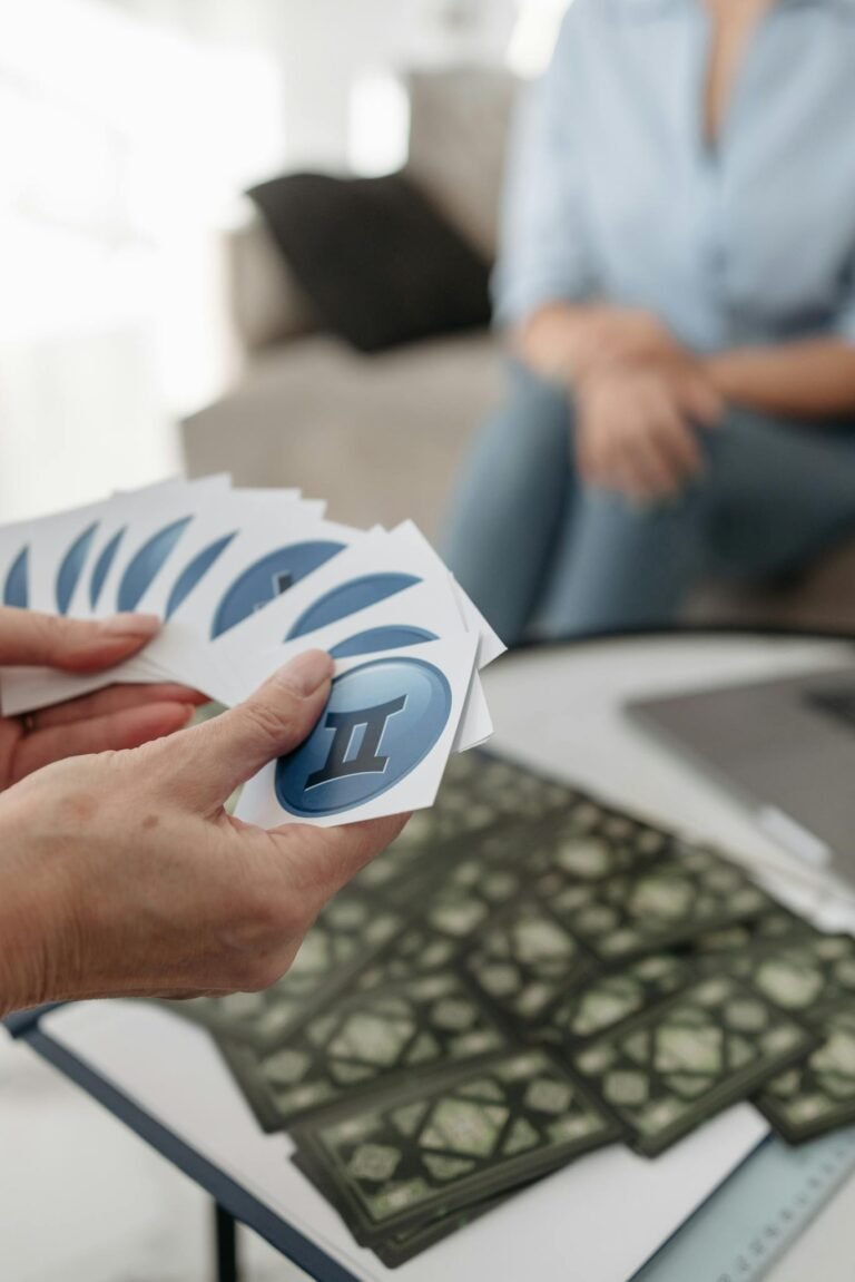 A person holding Gemini cards during a tarot reading session indoors, suggesting astrology and mystery.